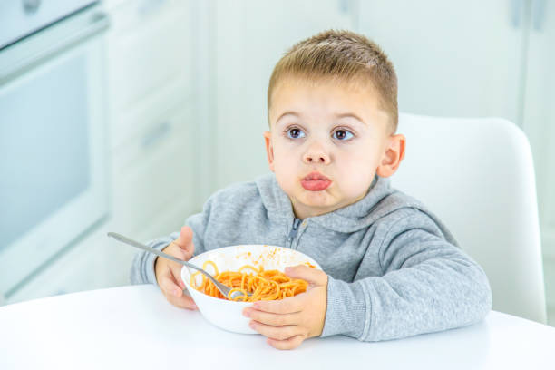 istock children in the kitchen at the table turning pasta. 1447151818