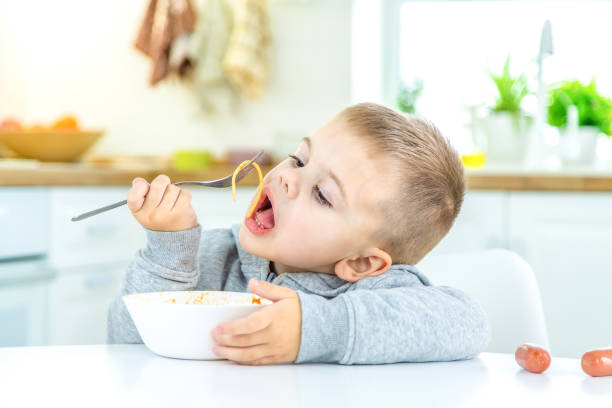 istock children in the kitchen at the table turning pasta. 1447151822