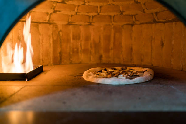 im ofen zum backen neapolitanischer pizza in einem gasbefeuerten klassischen italienischen pizzaofen mit hoher temperatur. krusten steigen schnell auf und toppings werden leicht verkohlt und knusprig. traditionell gebacken - lightly stock-fotos und bilder