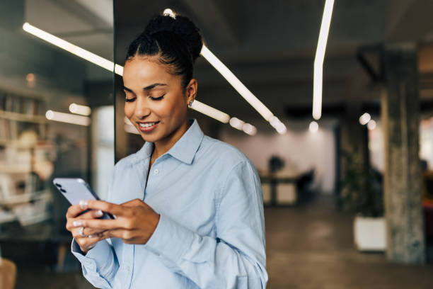 istock Beautiful African woman using a mobile phone at the office. 1447151984