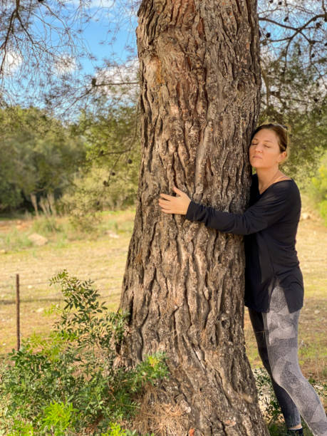 istock Woman with closed eyes hugging a tree trunk 1447152054