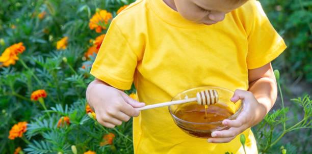istock child eats honey in the garden. Nature 1447153252