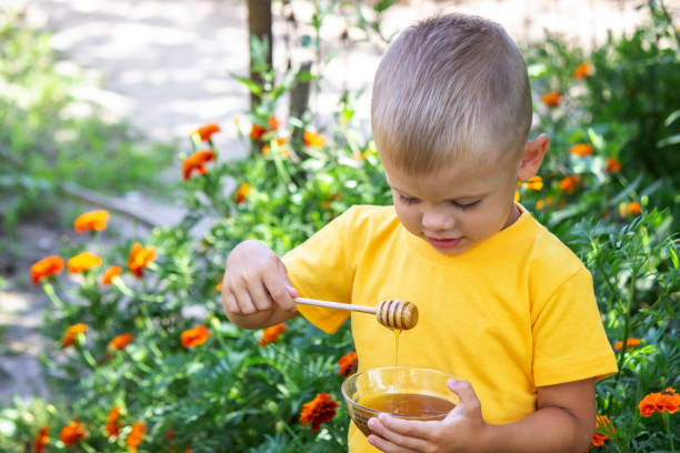 istock child eats honey in the garden. Nature 1447153257