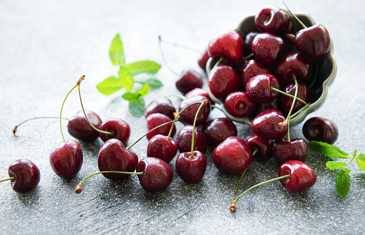 Fresh red cherries fruit in bowl on a concrete background