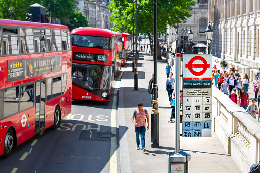 London, United Kingdom - June 22, 2018: Whitehall street with Horse Guards Parade bus stop, row of double-decker buses by cabinet government office