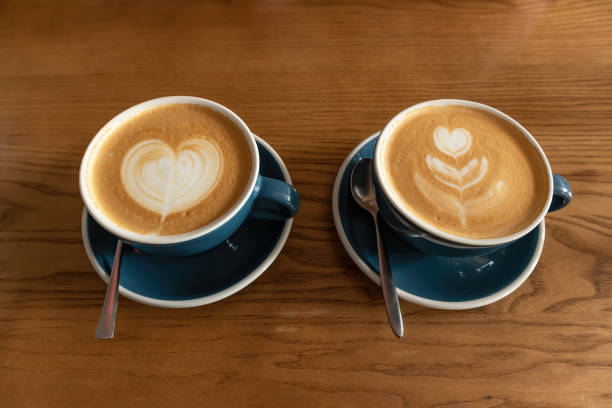 istock Two mugs with cappuccino coffee on a wooden cafe table 1447157851