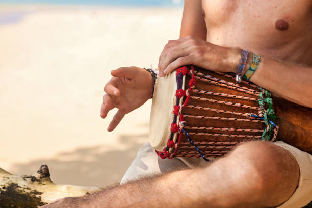 istock Close up hands young man drummer, playing rhythm on djembe drum on tropical sandy beach at sand background. Travel vacation and music relaxation concept. Selective focus. Copy text space 1447158363