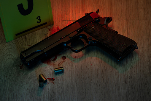 Hand gun with ammunition on dark background. 9 mm pistol military weapon and pile of bullets ammo at the metal table.