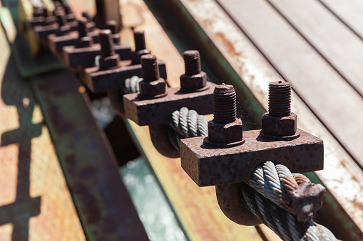 Rope with rusty bolt clamps, cable-stayed bridge details close up photo