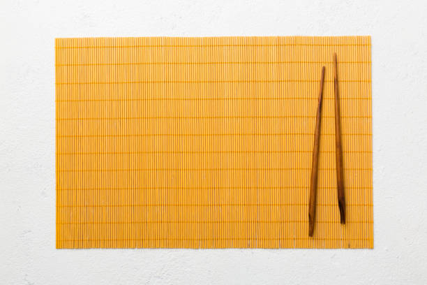 istock Two chopsticks and bamboo mat on cement background. Top view, copy space 1447163456