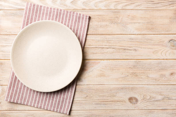 istock Top view on colored background empty round white plate on tablecloth for food. Empty dish on napkin with space for your design 1447163520