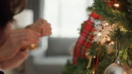 istock Closeup of women hands decorate the Christmas tree at home. 1447164922
