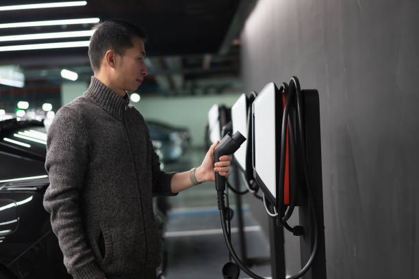 Man is preparing to charge electric car stock photo