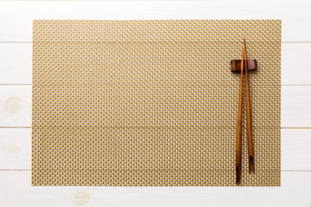 istock Two chopsticks and bamboo mat on wooden background. Top view, copy space 1447166423