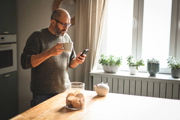 istock mature adult man working at home (kitchen, mobile phone) 1447168330