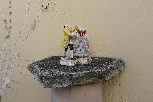 Broken porcelain figurines male and female figures wearing epoque clothing at waltz dance. Antique decorative objects.