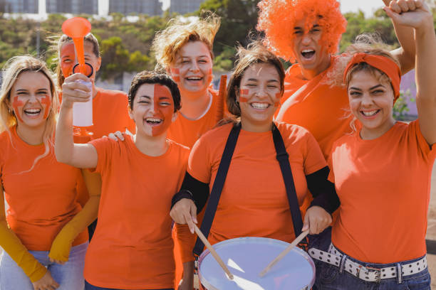 болельщики футбола смотрят футбольный матч на стадионе - люди в оранжевых футболках весело веселятся на спортивном чемпионате мира - fan dutch flag women colors стоковые фото и изображения