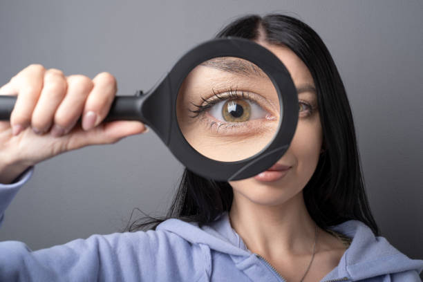 woman looking through a magnifying glass, searching for a finding concept . funny humor image - inzoomen stockfoto's en -beelden