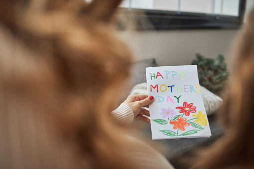 Mother and daughter are holding beautiful card made by a little girl for a Mother’s day.