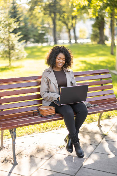 istock Young African woman using laptop outdoors on the park bench 1447181857