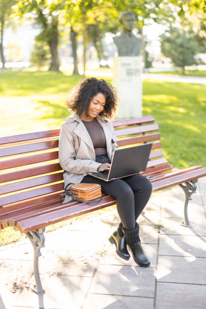 istock Young African woman using laptop outdoors on the park bench 1447182227