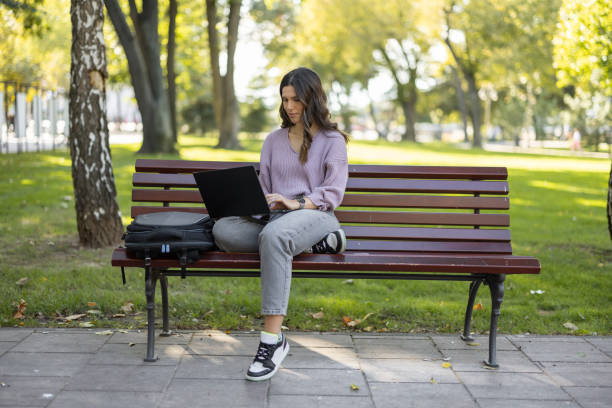 istock Female student using laptop in city park 1447183236
