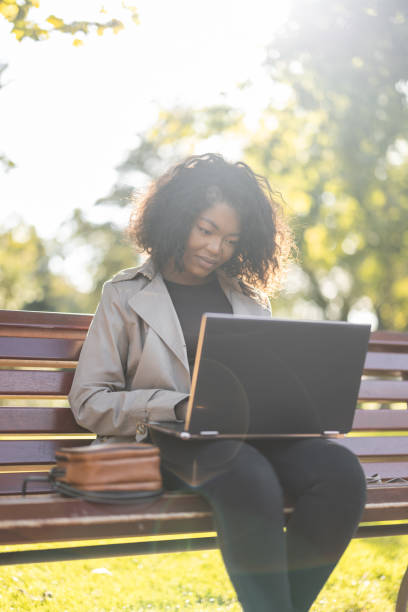 istock Young African woman using laptop outdoors on the park bench 1447183353