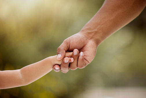 Care, support and holding hands for youth, trust and generation against a blurred background. Hand of parent and child arms in caring relationship, help and love for childhood growth and development