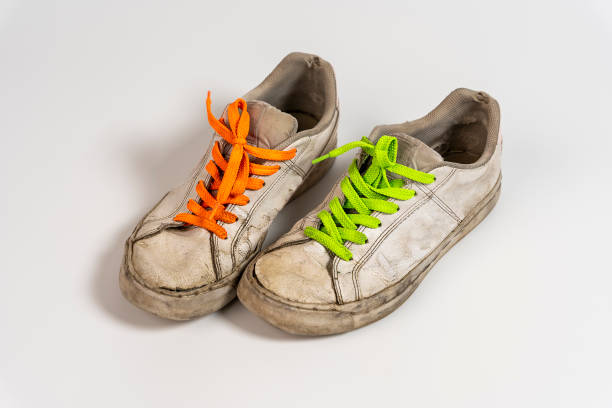 istock worn old torn white sneakers with colored laces on a white background 1447185459