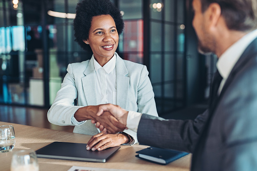 Businesswoman and businessman shaking hands across the table