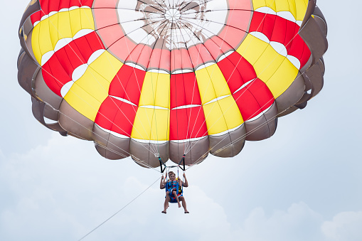 Yellow and orange paragliding on a blue sky with clouds on background
