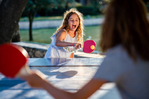 Happy girls playing table tennis on summer day
