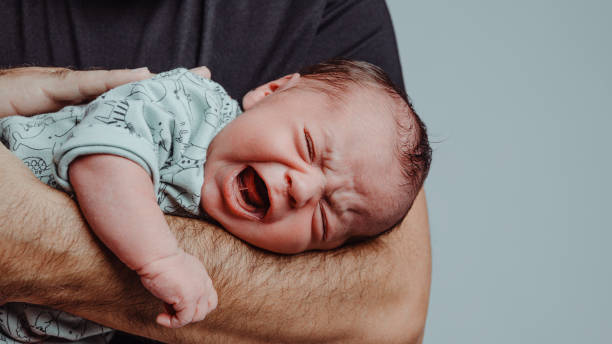 newborn on his father's arm screams crying with expression of suffering - huilen stockfoto's en -beelden