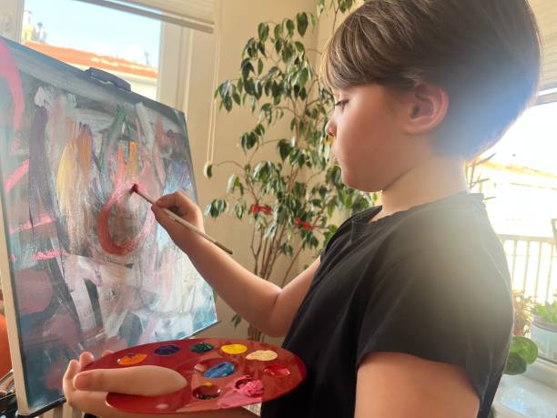 istock Kid painting with brush on canvas 1447198260