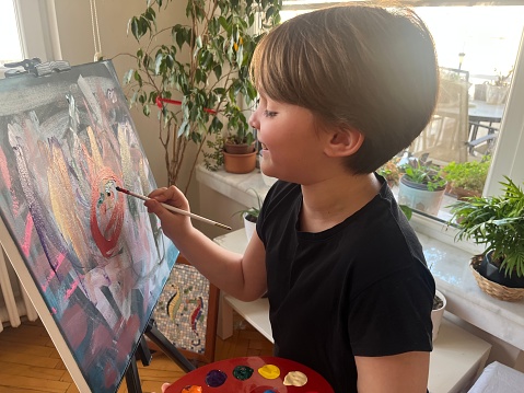 Kid painting with brush on canvas