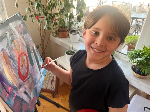 Kid painting with brush on canvas