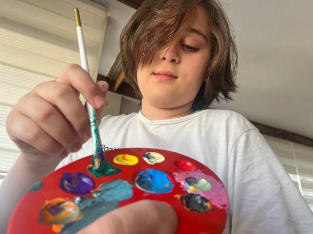 istock Teenage kid using paint palette with brush 1447198690