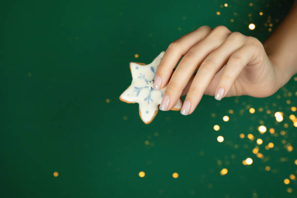 istock Women's hands hold a handmade gingerbread on a green background. 1447201606