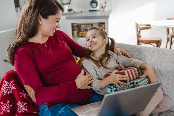 bella madre incinta che usa il computer portatile con la sua piccola figlia carina - human pregnancy clothing shopping retail foto e immagini stock