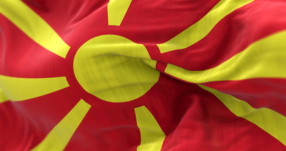 Close-up view of the North Macedonia national flag waving in the wind. Republic of North Macedonia is a country in Southeast Europe. Fabric textured background. Selective focus. 3D illustration
