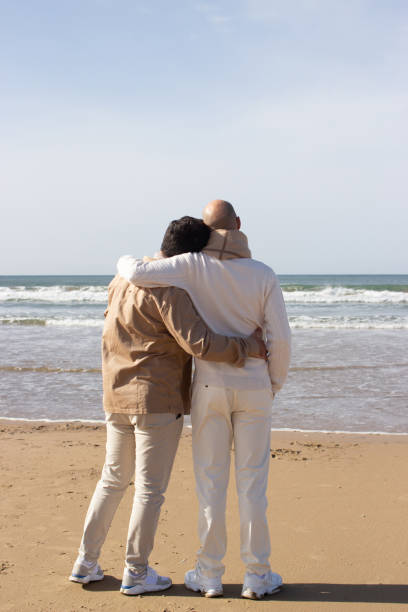 istock Stylish gay couple looking at sea waves 1447209651