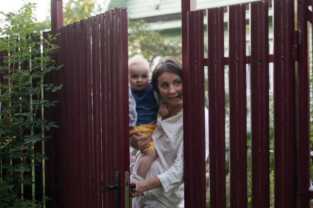 ciekawska kobieta z dzieckiem podgląda bramę ogrodzenia - fence child neighbor peeking zdjęcia i obrazy z banku zdjęć