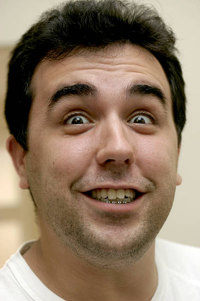 Brazilian young man smiling and grimacing using orthodontics brace. 