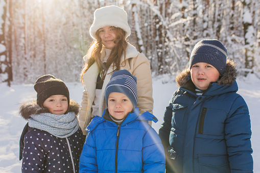 Children play and have fun in winter forest. Happy childhood. Winter holiday. Deep snow. Boys and girls. Group portrait. Warm clothes