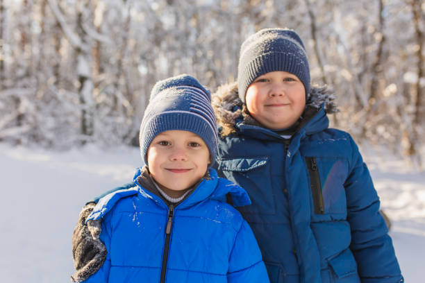 冬の森にジャケットと帽子をかぶった女の子と男の子のポートレート。子供。幸せな子供時代。冬休み。深い雪。暖かい服装 - 6 11 months ストックフォトと画像