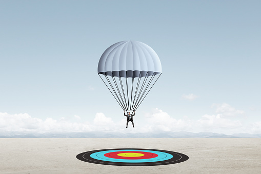A businessman descends from the sky wearing a parachute as he is about to land on his target.
