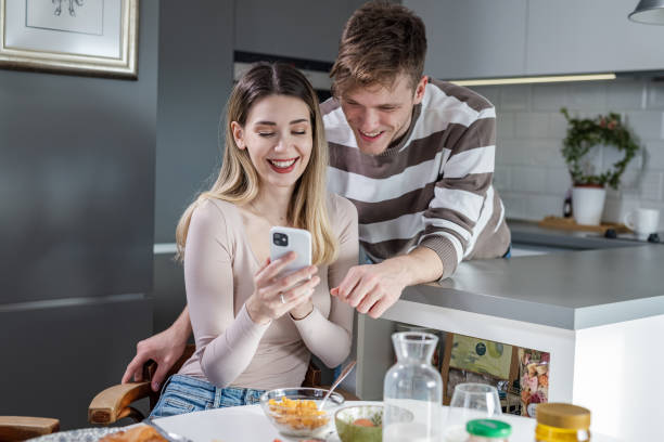 istock Young couple using mobile phone while having a breakfast. Sunday morning at home. 1447224480