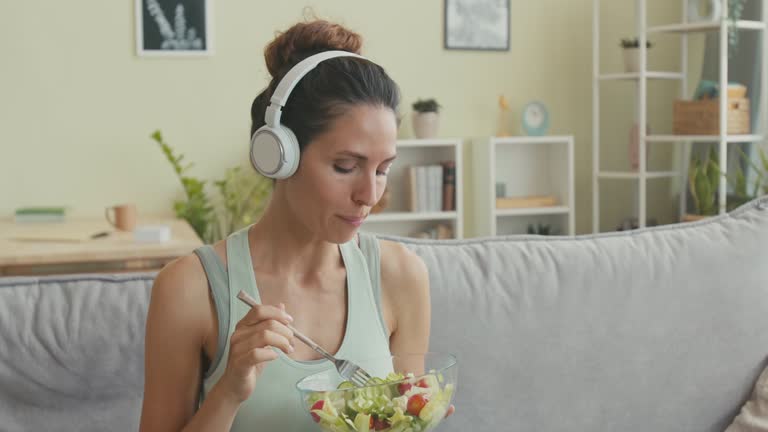 Woman Listening to Music in Headphones while Having Healthy Lunch