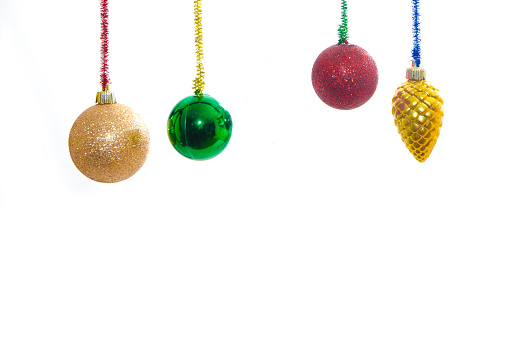 Multi-colored Christmas ball and bauble ornaments and decorations in the colors purple, blue, green, pink and red with a silver top and silver ribbon hanging in a row on an isolated white background. Shot with a DSLR camera 1Ds Mark III. Banner or horizontal orientation.