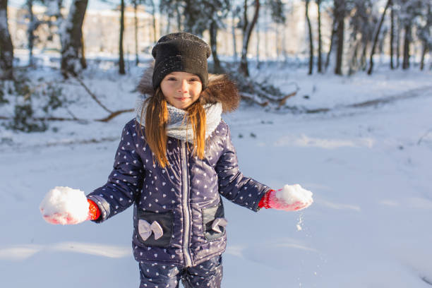 menina jogar bolas de neve e se divertir na floresta de inverno. correndo e se movendo. infância feliz. férias de inverno. neve profunda. raparigas. roupas quentes. jogue neve - snowball snow play throwing - fotografias e filmes do acervo